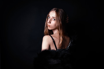 White woman in fur boa on black backdrop 