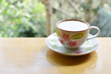 Obraz premium Hot coffee cup with spoon put on wood table with blur background, refreshment on morning time, relaxing in the coffee shop,