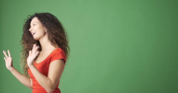 Excited young woman dancing over green background