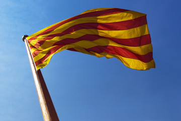 Catalonia flag on a pole is fluttaring on a blue sky background.