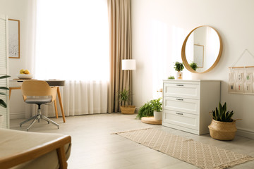 Stylish room interior with chest of drawers and round mirror