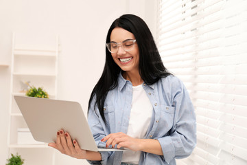 Beautiful young woman working with laptop indoors