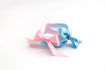 Two pink and blue bow bracelets lie on a white background. Symbol of the sexual identity of the boy and girl.
