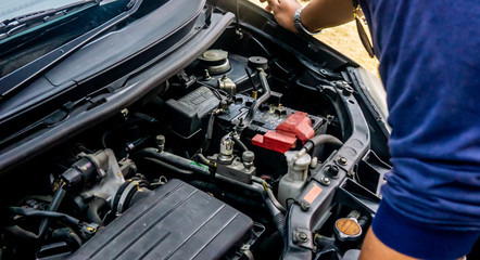 Hand of technician checking out and do a maintenance on the car engine outdoor.