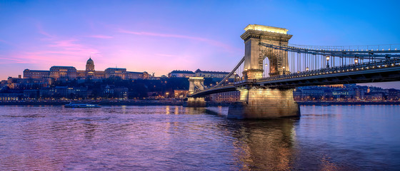 Panoramic photo about Buda castle and Chain bridge with danube river. Amazing purple sunset lights. Budapest, Hungary.