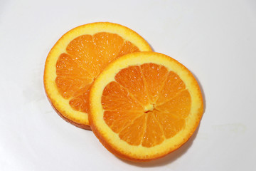 Fototapeta na wymiar Two thin round pieces of orange slices on white plate.