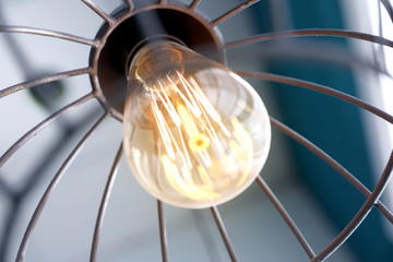 Stylish metallic pendant lamp with Edison light bulb indoors, closeup