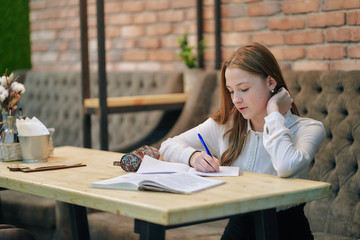 girl teen student preparing for classes in a cafe