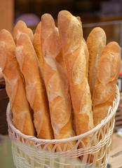 Natural wicker basket with freshly baked baguettes on blurred background. Home baked tasty delicious crusty bread on the counter of a home village bakery. 