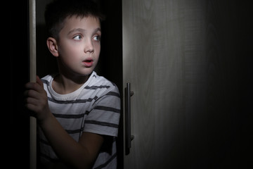 Scared little boy hiding in wardrobe. Domestic violence concept