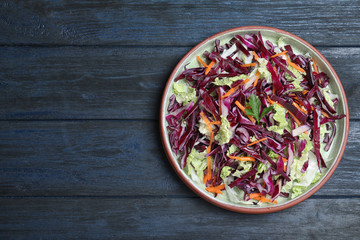 Fresh cabbage salad served on blue wooden table, top view. Space for text