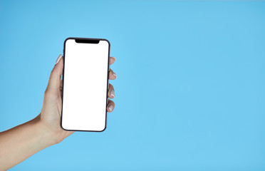 Woman hand holding black cellphone with white screen on a yellow background. Smartphone mockup