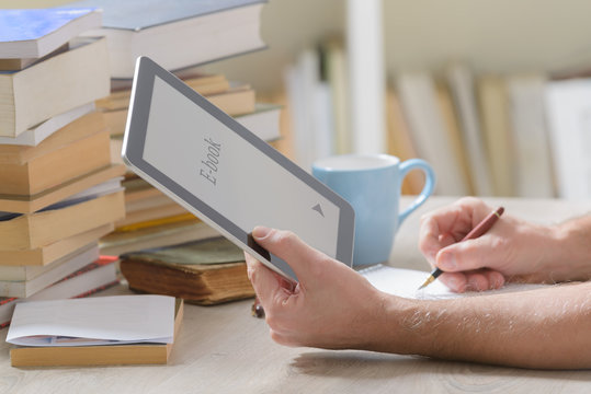 Man holding a modern ebook reader and book in library