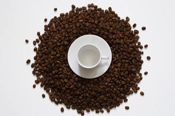 white cup on coffee beans on a white background, top view