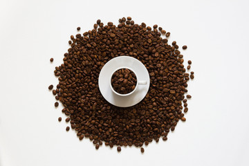 white cup on coffee beans on a white background, top view