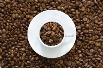 white cup on coffee beans on a white background, top view