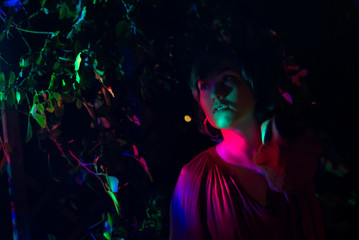 Young woman in the garden illuminated by multi-colored light.	
