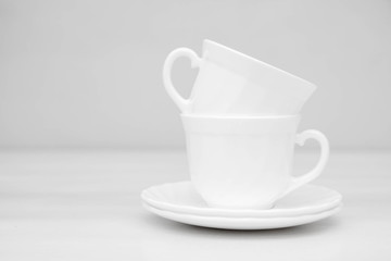 White ceramic cups with saucers on white table. Space for text