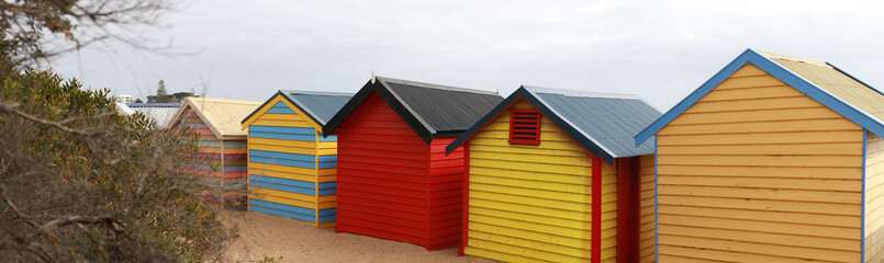Fototapeta na wymiar views of rows of colourful beach bright painted summer holiday bathing box's along a sandy beach on a sunny day, Brighton beach, Melbourne Victoria
