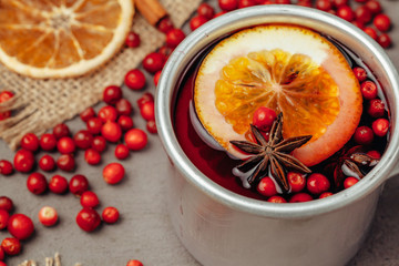 Close up of mulled wine cup with spices and berries on grey table