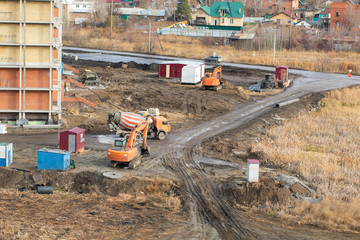 Details of construction site. heavy industrial machinery works on construction site: concrete mixer, bulldozer, excavation.