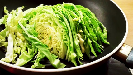 A cut green cabbage in a pan