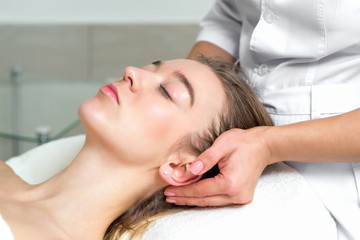 Young woman receiving a head massage by female beautician in the spa beauty salon close up.