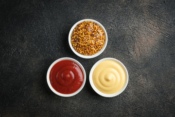 Set of popular sauces - mustard, ketchup and mayonnaise on a dark background. Top view free copy...