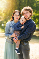 Fototapeta premium Family life. Portrait of parents and their son on the background of nature. Walk in park.