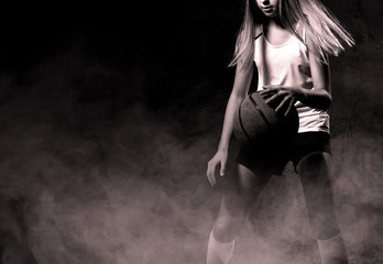 Beautiful caucasian teen woman in sportswear playing basketball . Sport concept isolated on black...