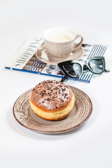 Fresh doughnut with coffee, glasses and fashion magazine