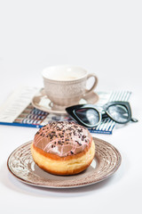 Fresh doughnut with coffee, glasses and fashion magazine