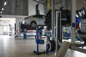 Fototapeta premium General plan of the car service station. The posts and lifts with the cars in blur, the background image of the service center.