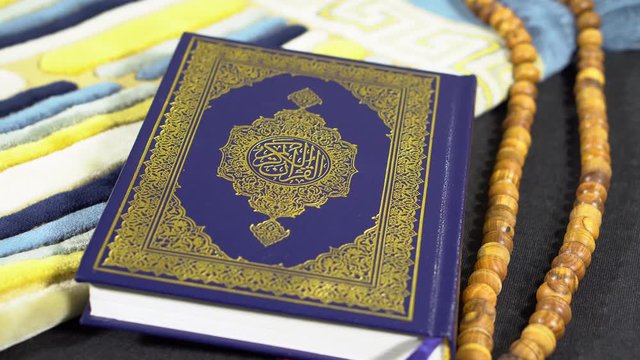 Rotating Shot of Muslims Holy Book Quran Al Kareem with wooden paternoster Tasbeeh and prayer rug janamaz