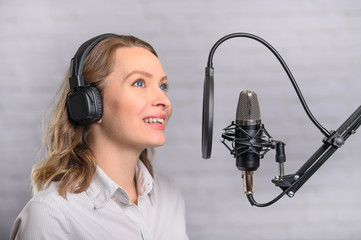 Female vocal recording. Young girl with microphone and headphones in recording studio. Recording of...
