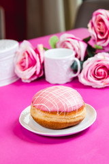 Obraz na płótnie Canvas Fresh doughnut on a pink background, flowers and decorations