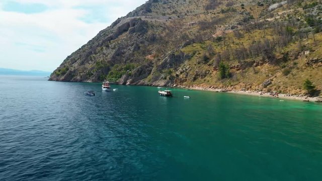 Aerial drone footage close to coastline with rocky hills. Passing boats in a bay, Croatia - stock video