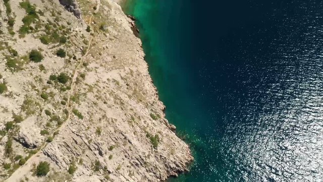 High angle aerial drone footage. Flying above the coastline with the camera slowly tilting up.