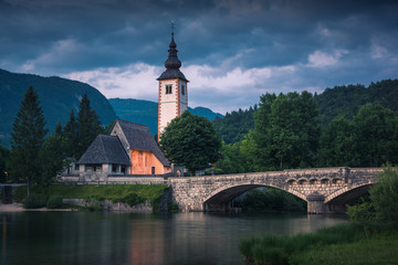 Church and stone bridge over the Bohinj lake in Julian Alps, Triglav National Park, Slovenia