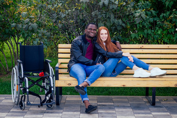 travel insurance concept.international couple in love sitting on the bench in park next to wheel chair