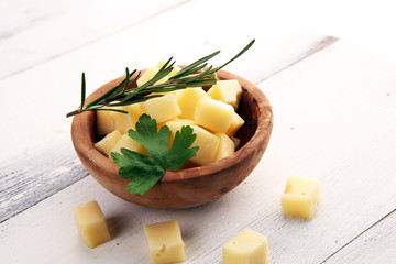 cheese cubes in wooden bowl with parsley. cheese pieces on table