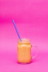 Fresh healthy fruit smoothie in a jar on a pink background