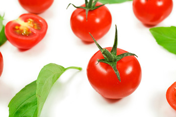 Ripe red tomatoes with basil leaves isolated on a white background.