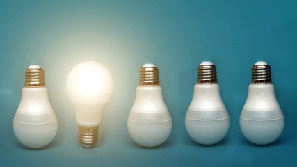 A white light bulb glows among the others. concept ideas. stands out among others. a bright lamp shines