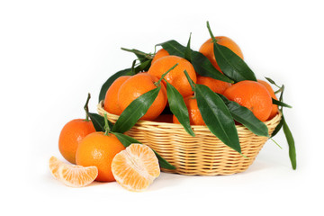 Fresh clementines with green leaves in a braided basket isolated on white background