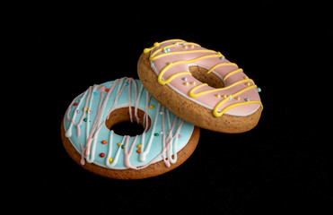 Two gingerbread in the form of a donuts on a black isolated background.