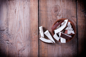 Ceramic bowl with coconut slices on a wooden background.