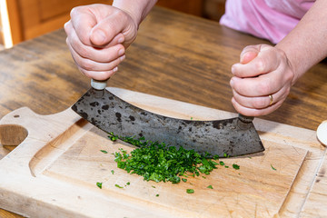 Woman chopping parsley in her kitchen