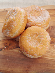 Three fresh jam doughnut on a wooden board, Pastry product.