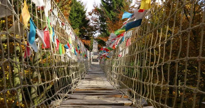 Himalayan sidewalk deep in nature Skywalk wooden construction of pass hitting by strong wind tree trunks colored flags during a sunny autumn day captured in Radhost Pustevny area slow motion 4k 60fps